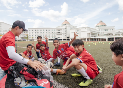 After playing, teacher and students sitting in field